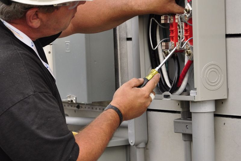 Electrician installing an electrical meter base on a wall